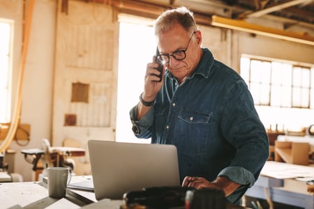 Business owner on the phone and looking at laptop