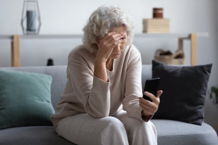 Senior woman holding phone and looking frustrated