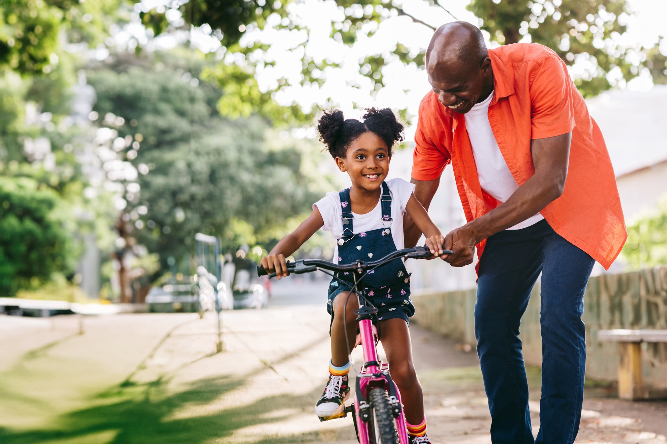 Man teaching daughter how to ride a bike.